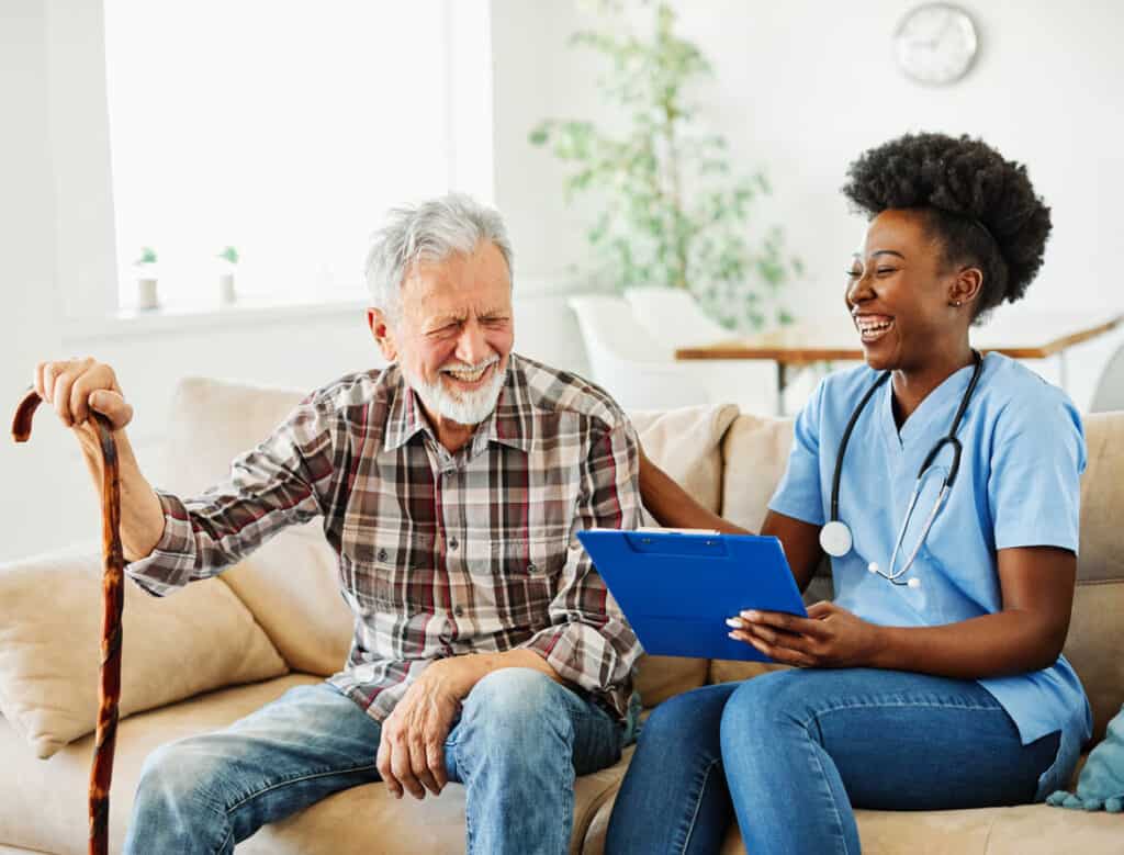 Caregiver statistics 2015 - a nurse caregiver laughing with a senior man at home