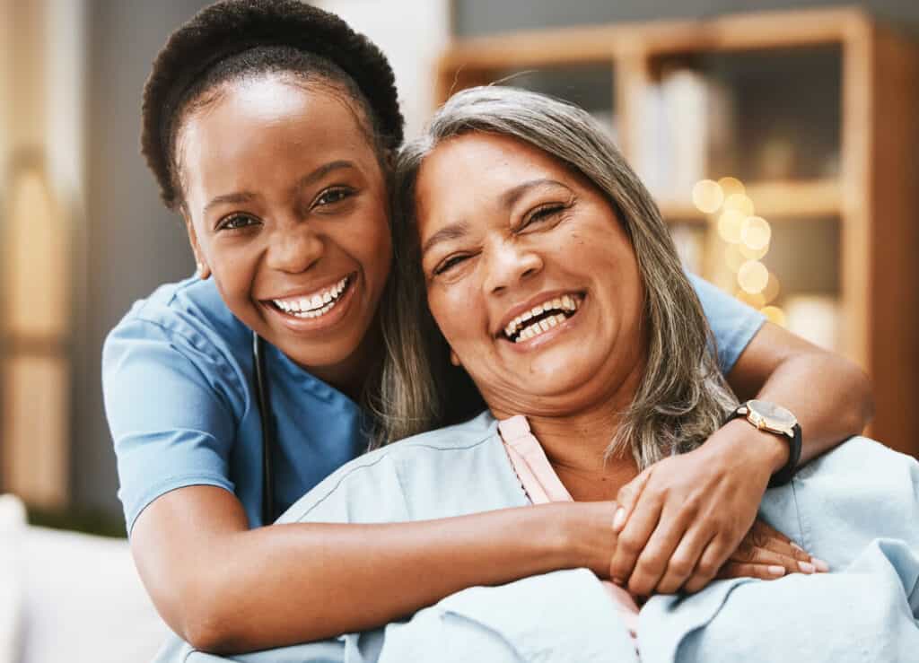 Caregiving in the US - a female caregiver smiling while hugging a female patient