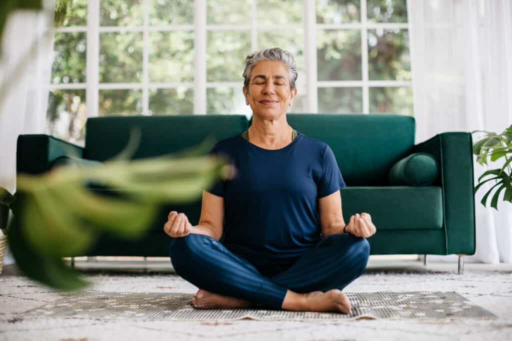 an elderly woman meditation at home as part of her daily exercise routine