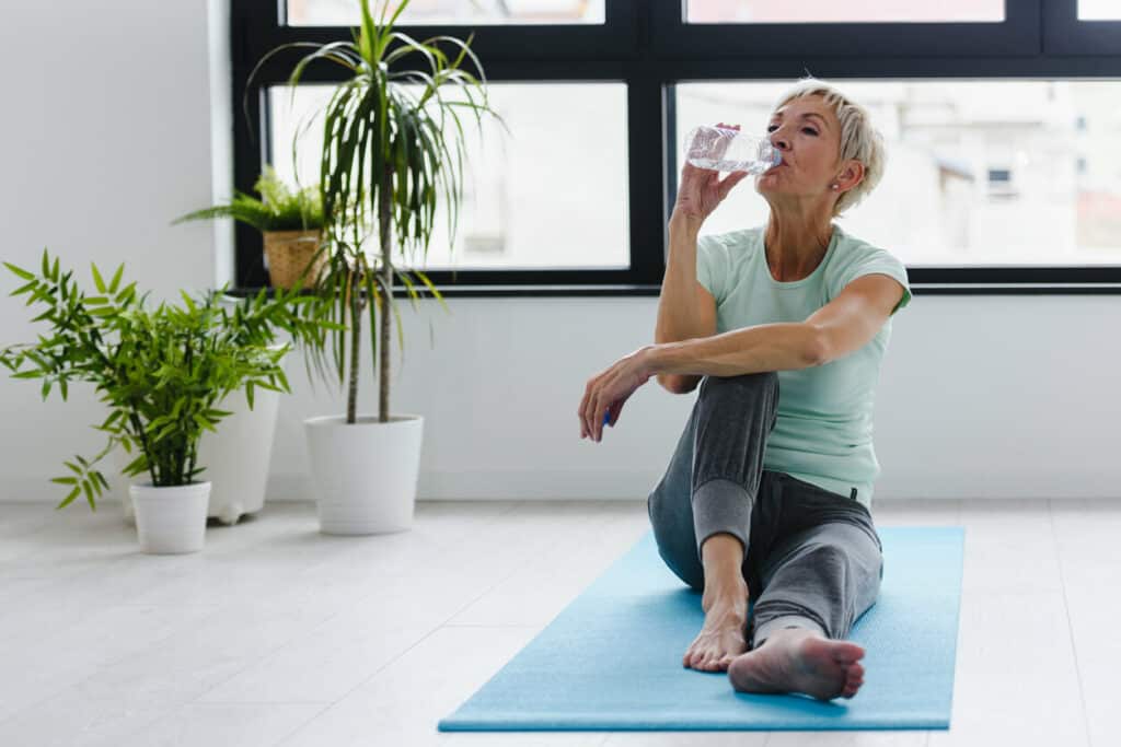 older woman staying hydrated during yoga | free exercise videos for seniors
