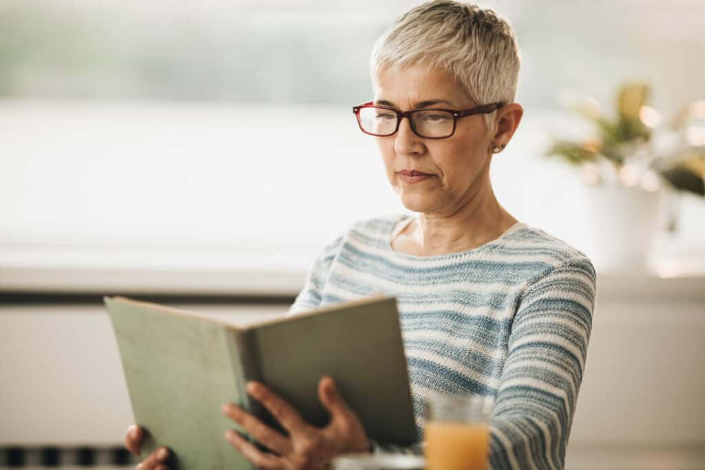 middle-aged woman reading a book to manage caregiver stress