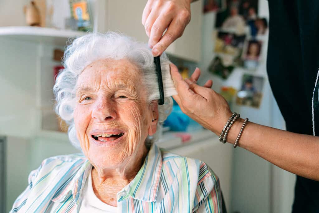 caregiver brushing the hair of an aging woman