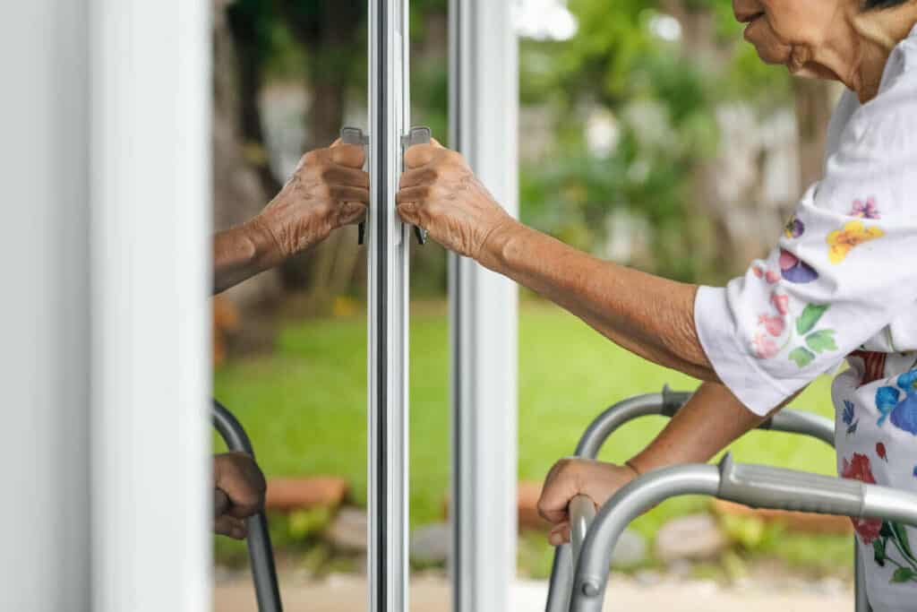 Elderly woman with a stroller opening a door at her home | A helpline for senior citizens can be a valuable aid in knowing how to make your loved one’s home safe.
