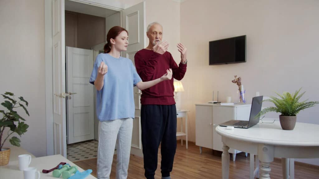 a caregiver helping an elderly man with his standing balance exercises