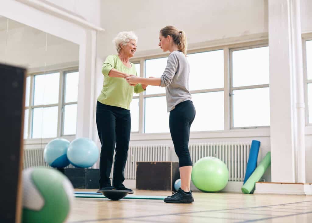 a caregiver helping an elderly woman with balance activities for adults