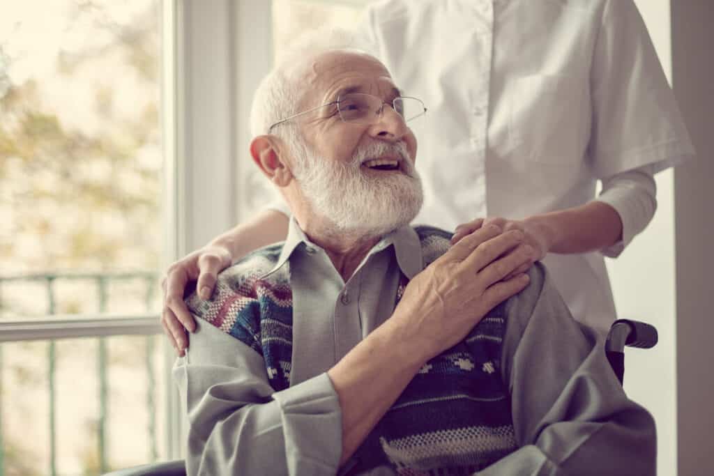 Mental illness caregivers - a smiling senior man holding his caregiver’s hand.