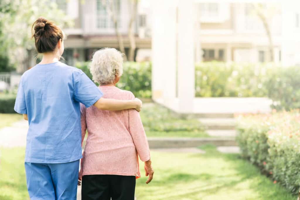 Being a caretaker - a female caregiver walking a senior patient outdoor.