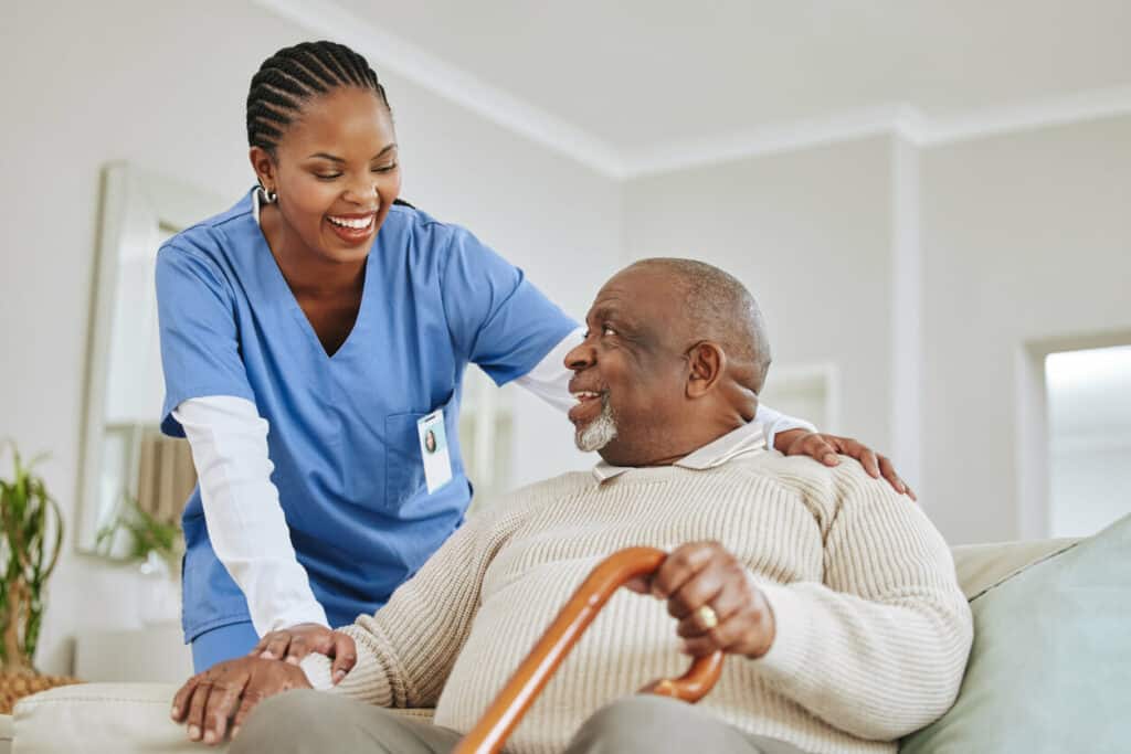Carry caregiver - a female caregiver and a male older patient smiling at each other.