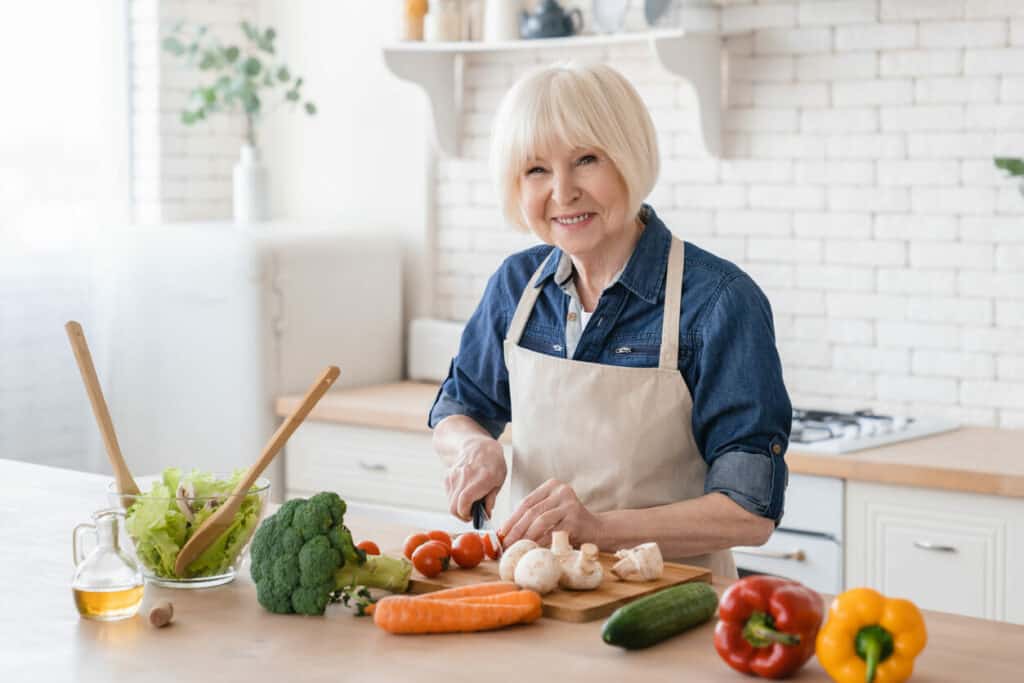 Elderly white female slicing vegetables for a brain-fit recipe