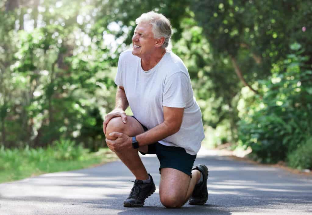 Benefits of exercise for elderly - a senior man holding his painful knee.