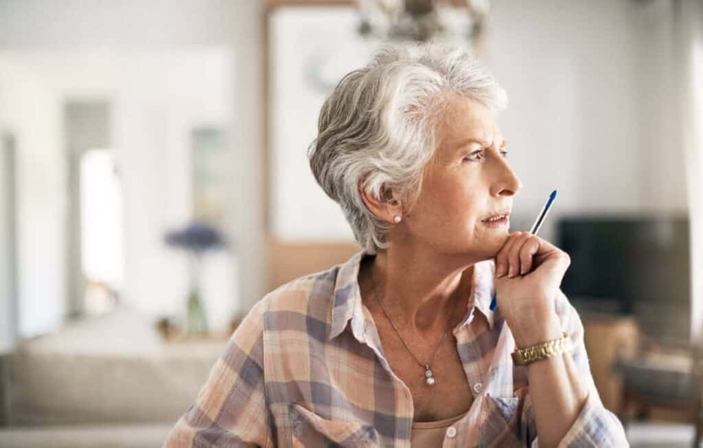help for fraud victims - a senior woman taking notes while recalling the scam situation.