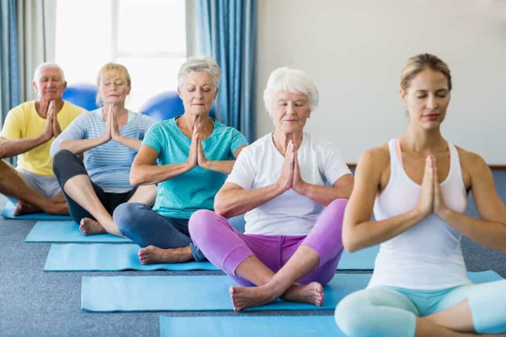 Senior residents in a long-term care facility doing yoga with a yoga instructor.