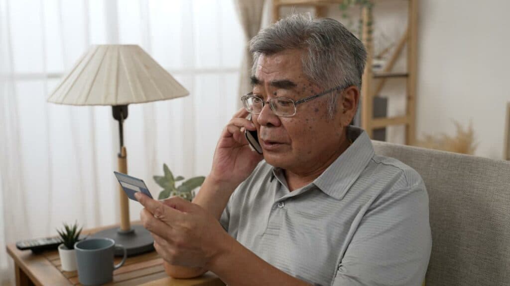 A senior man calling their bank after suffering an online scam | Tech should reimburse victims of online theft