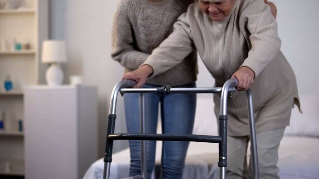 an in-home care provider assisting an older person using a mobility device after an injury
