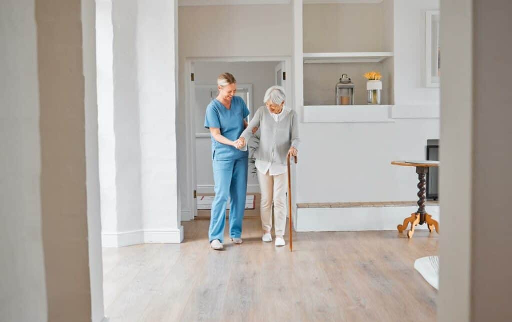 A senior woman with a walker being assisted by a caregiver - assisted living with memory care.