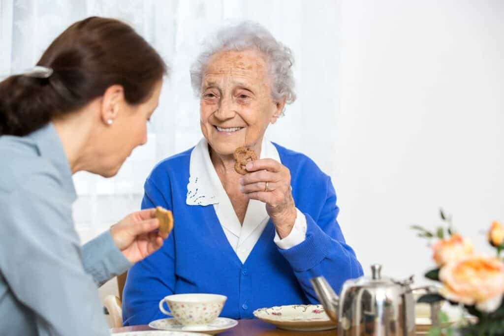 home caregivers prepare meals and eat with the seniors- home care assistance