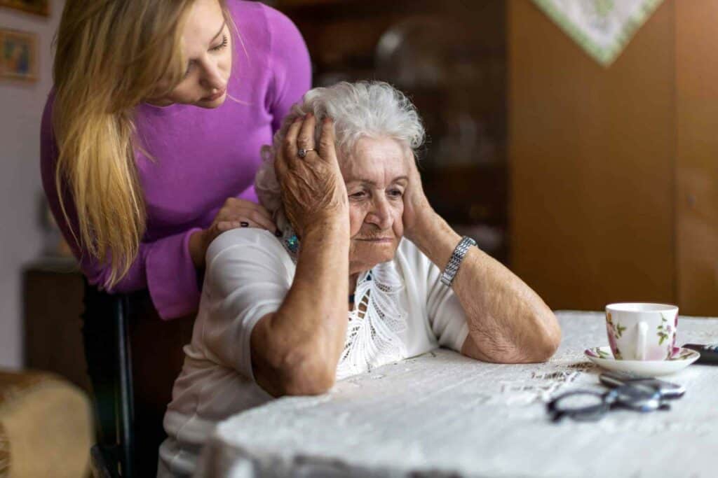 A senior who is confused and her caregiver consoling her - sundowning dementia.
