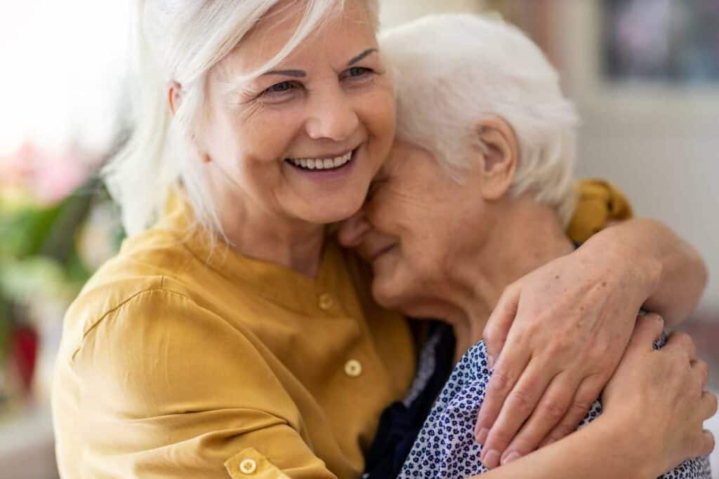 mature woman hugging elderly mother - who pays for assisted living for the elderly
