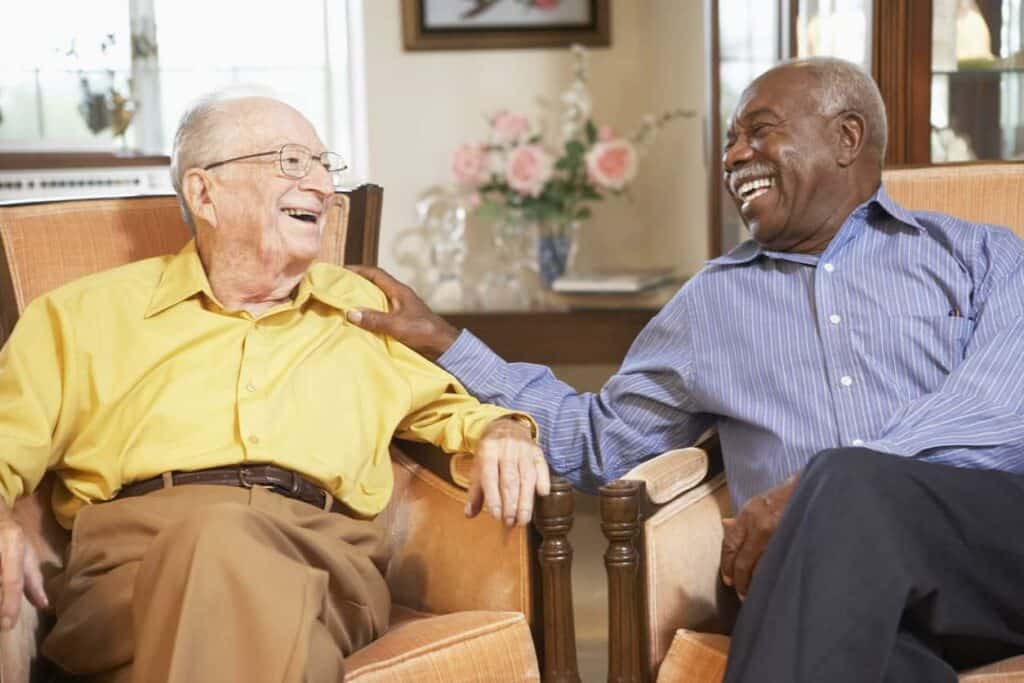 Assisted living facilities vs. nursing homes: two seniors talking and laughing at an assisted living residence