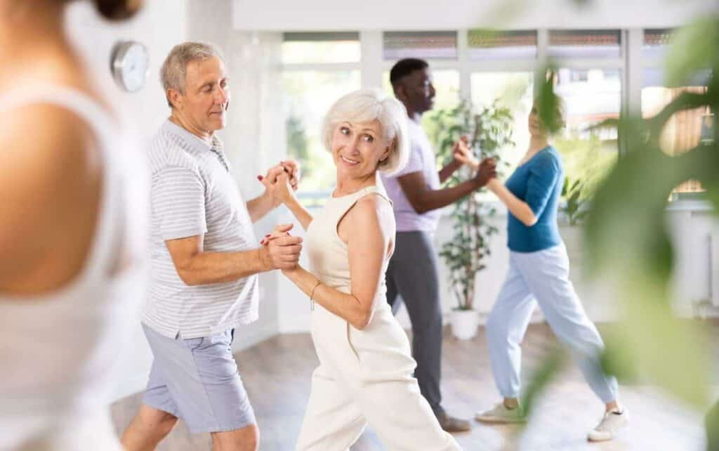 Assisted living vs. long-term care: two seniors having a dance class as part of an assisted living residence’s activities program