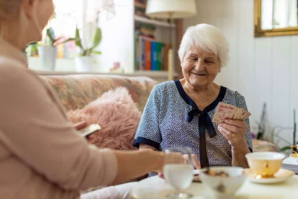A senior woman with dementia playing cards with her caregiver - dementia stages.