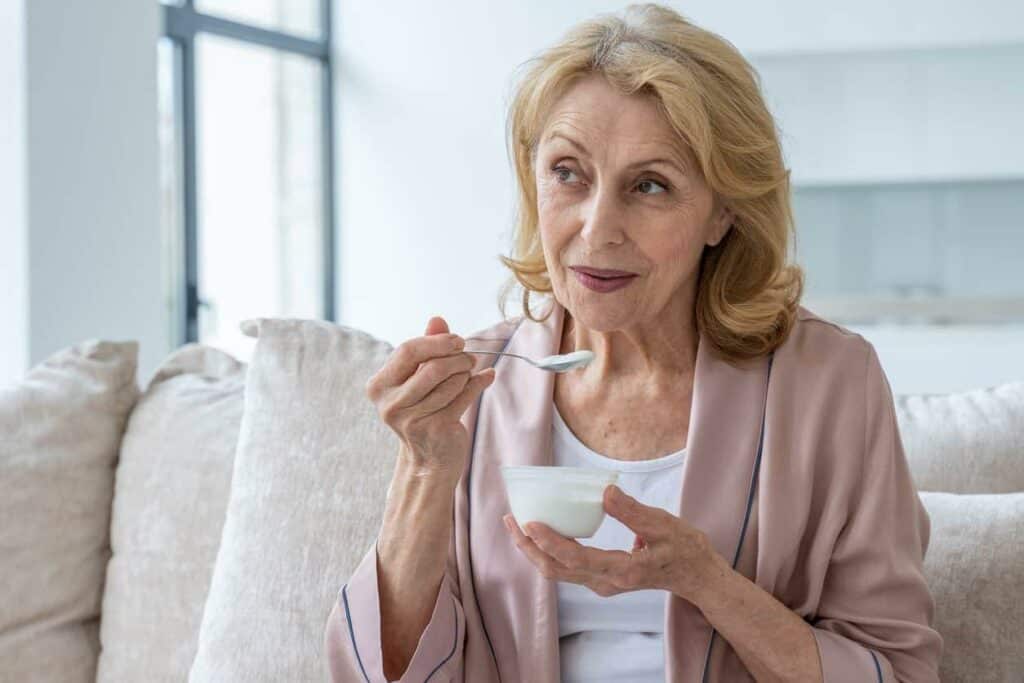 older woman eating yogurt to increase her calcium intake