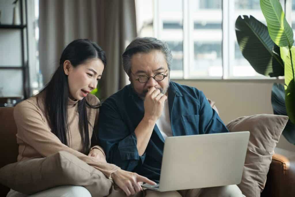 Aging Asian father and his daughter considering different senior home health care services options in a computer