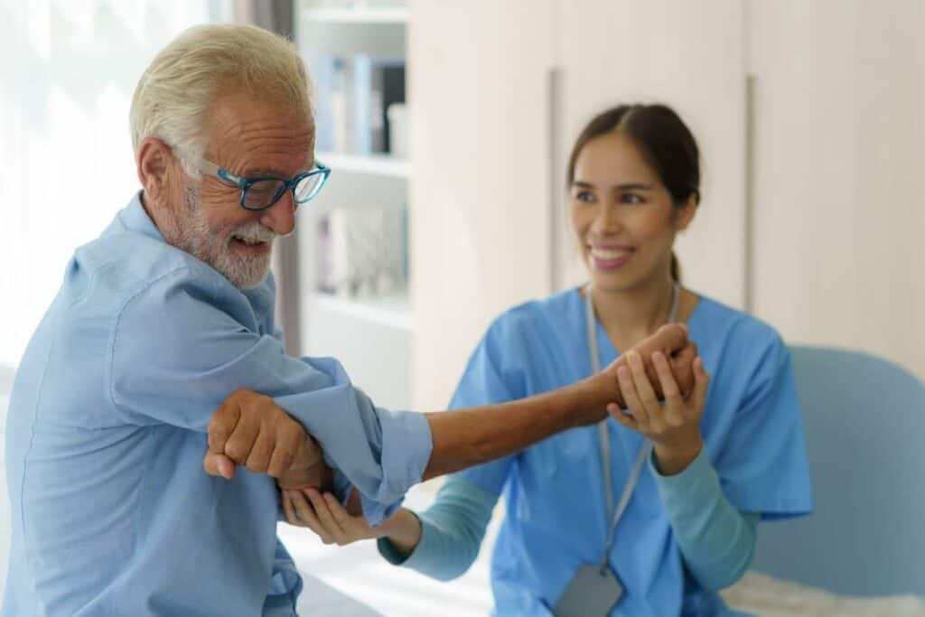 A female nurse assisting a senior with mobility exercise through in home health care.