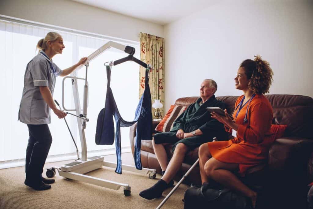 a caregiver preparing a Hoyer lift ready to transfer a senior to his bed
