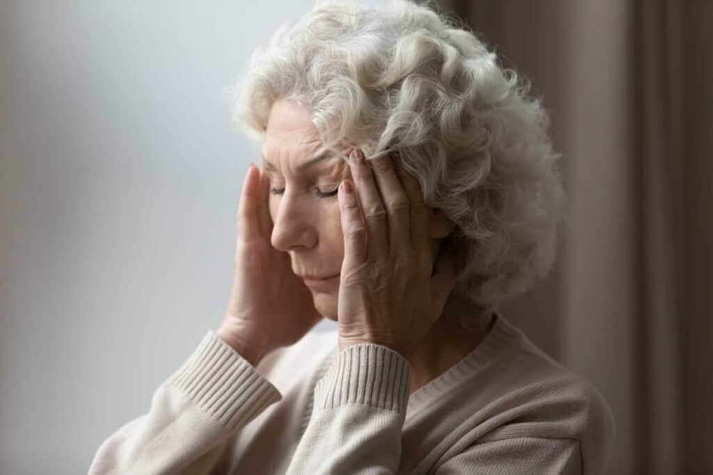 Older woman holding her head with her hands - dementia stages and symptoms