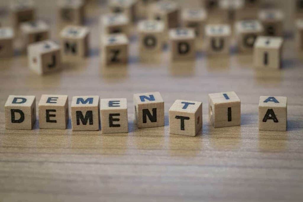 Word Dementia made of wooden cubes near alarm clock - dementia stages timeline