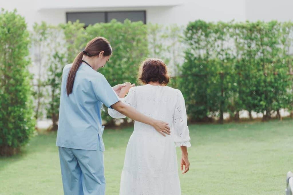 a young nurse assisting an older woman with her walk at assisted living for senior citizens