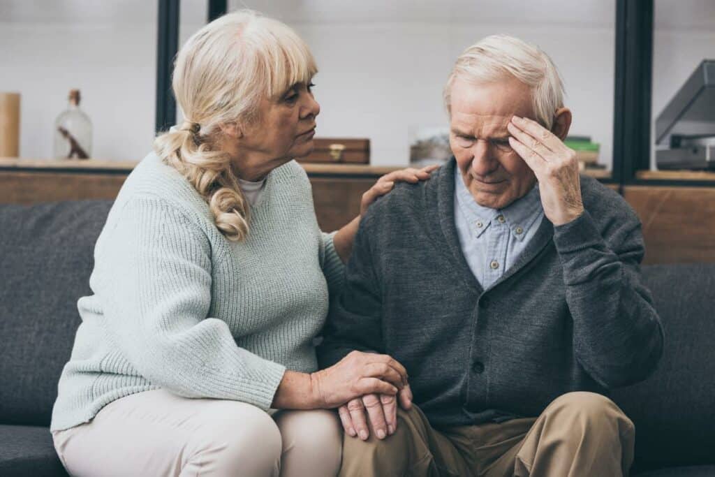 a senior woman consoling her husband after he started showing dementia symptoms