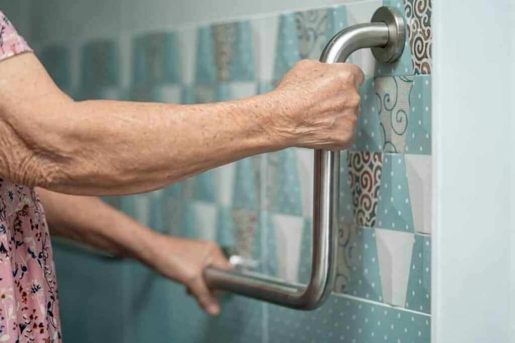 Elderly woman grabbing a shower standing handle in the bathroom