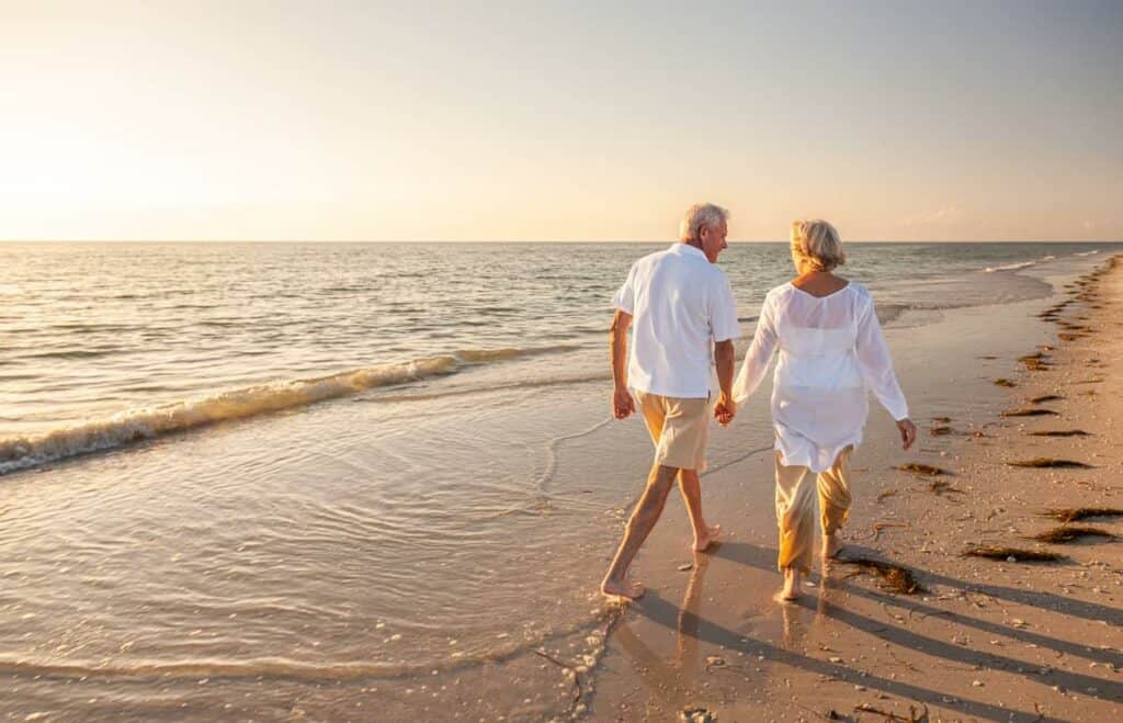 An older couple enjoying a beach walk as they contemplate nursing home long-term care