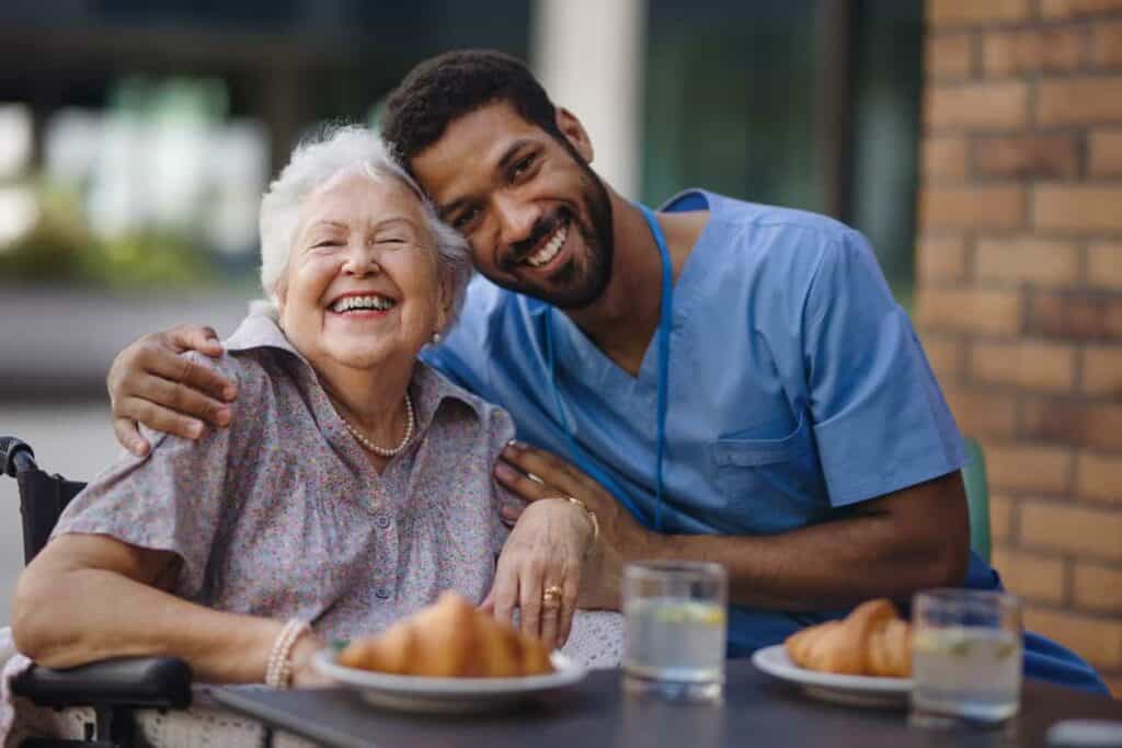 male caregiver and elderly woman smiling together in an assisted living residence