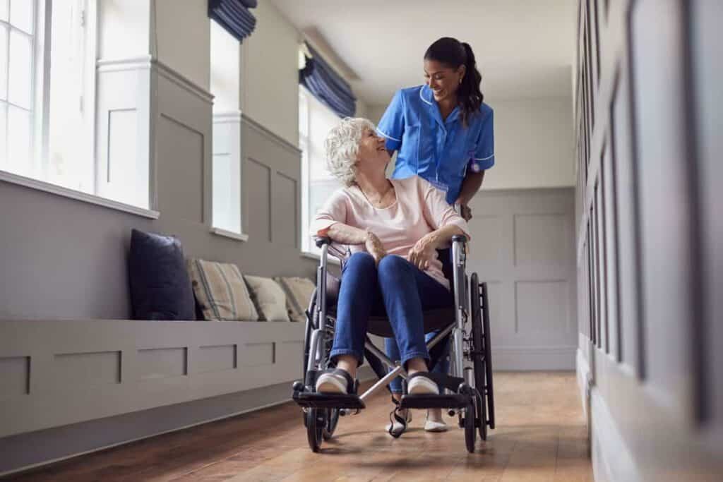 skilled nursing homes - caregiver helping an elderly woman move around in a wheelchair