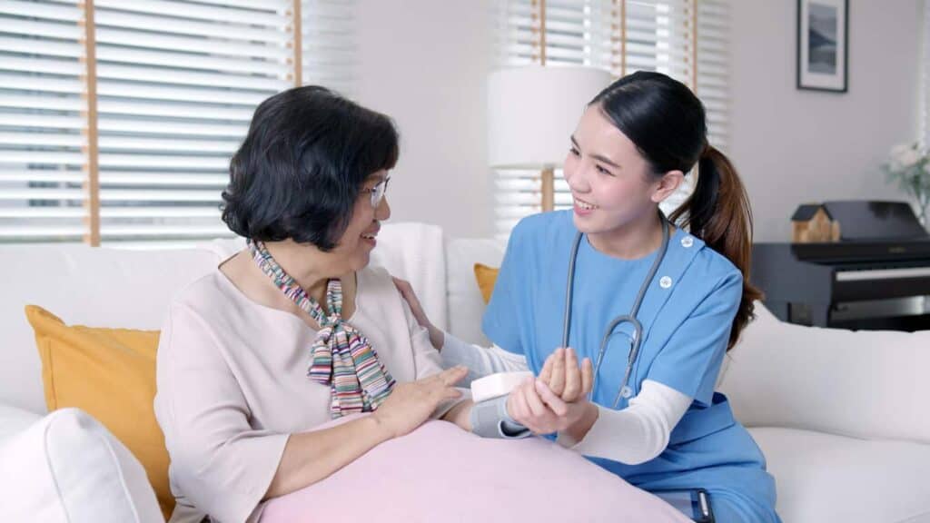Asian female nurse caregiver taking the blood pressure of her female senior patient at a remodeled old nursing home