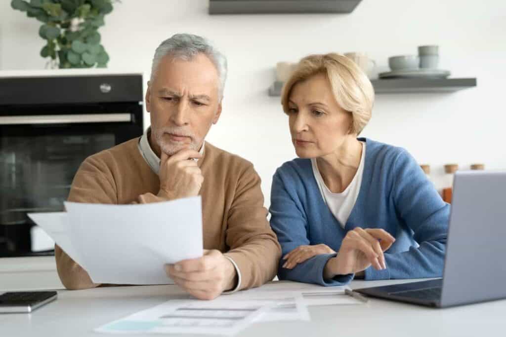 Elderly married couple looking at their financial information and considering these data to decide if they opt for a medical nursing home for both