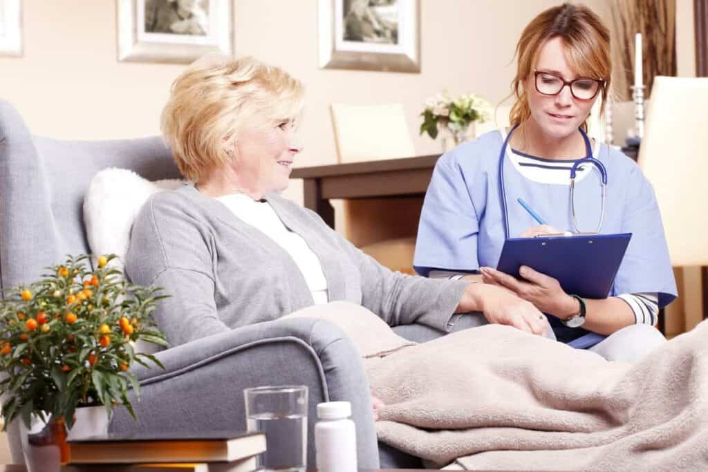 Senior female recovering after surgery at her home and being given a checkup by her female nurse caregiver | Nursing home meaning