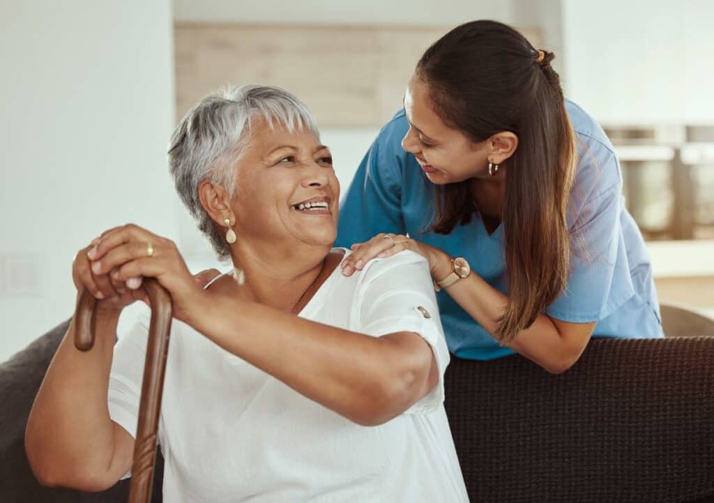 Black female senior and her caregiver sharing a laugh at a nursing home's living room | Nursing home definition