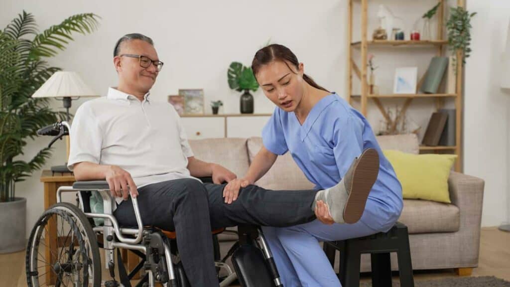 agency for home health care - female caregiver attending to a senior man in a wheelchair