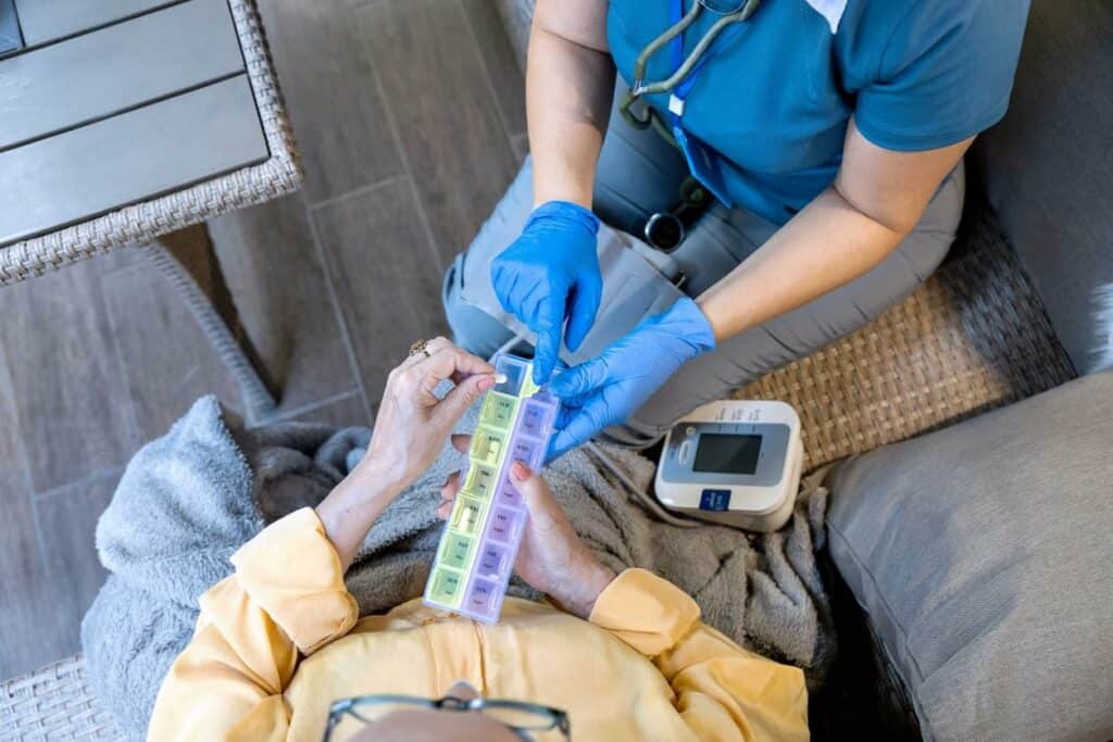 Caregiver giving medication to a patient under palliative care in assisted living home - palliative medicine