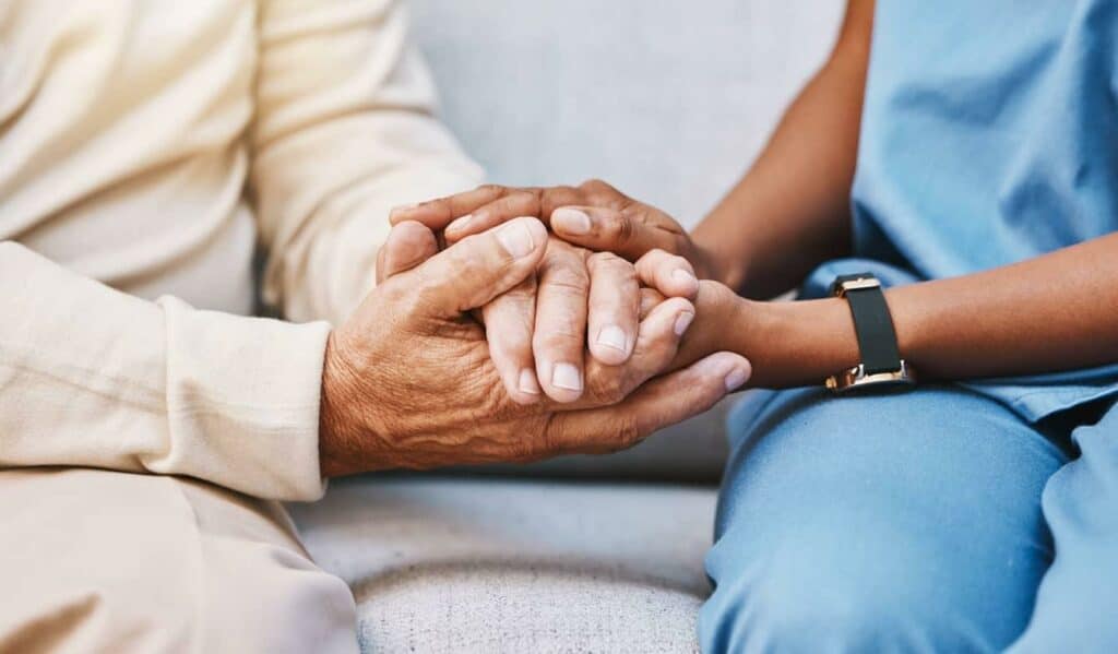 palliative nurse and patient holding hands in empathy - palliative care principles