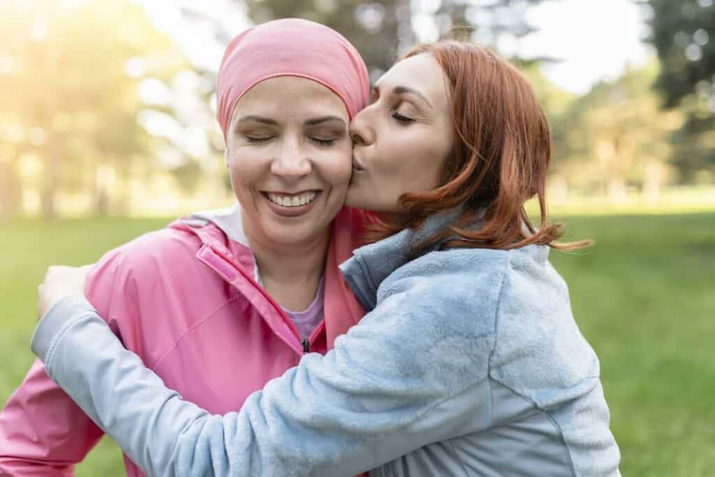 palliative chemotherapy meaning - a daughter hugging and kissing her mother undergoing chemo treatment