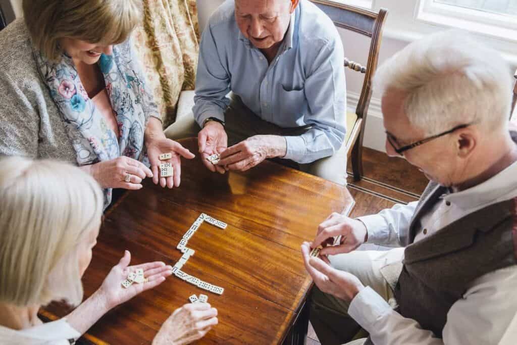 Seniors are playing dominoes together on a table - sierra place senior living carson city