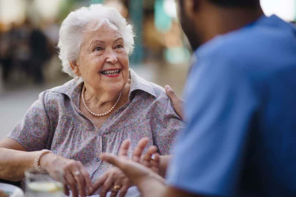 A senior woman happily talking to her caregiver at a cafe - Nevada caregivers.