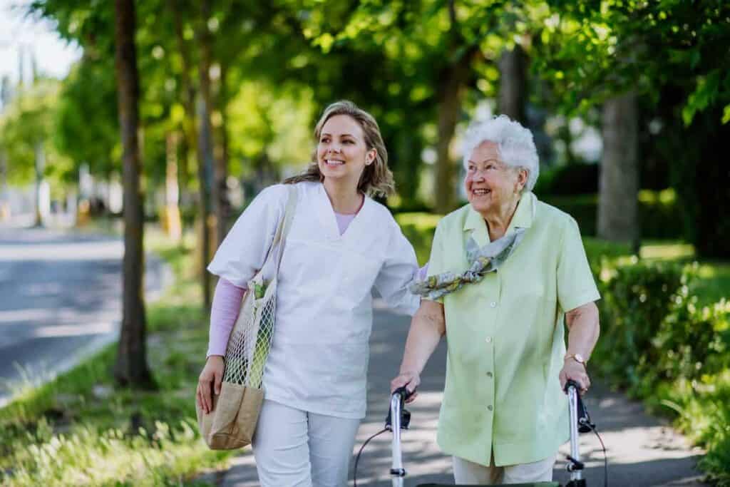 A caregiver with a senior woman enjoying a walk at a park - caregiver requirements in Nevada.