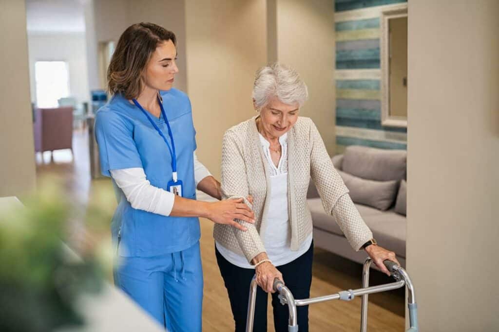 in home care careers/ a nurse assisting an older woman with her walk