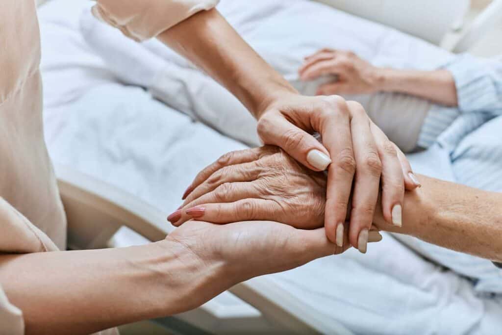 Palliative care doctor holding hands of a senior patient